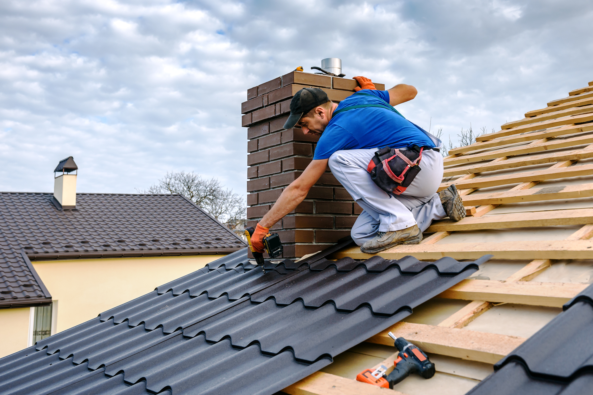 A man installs roofing on a house
